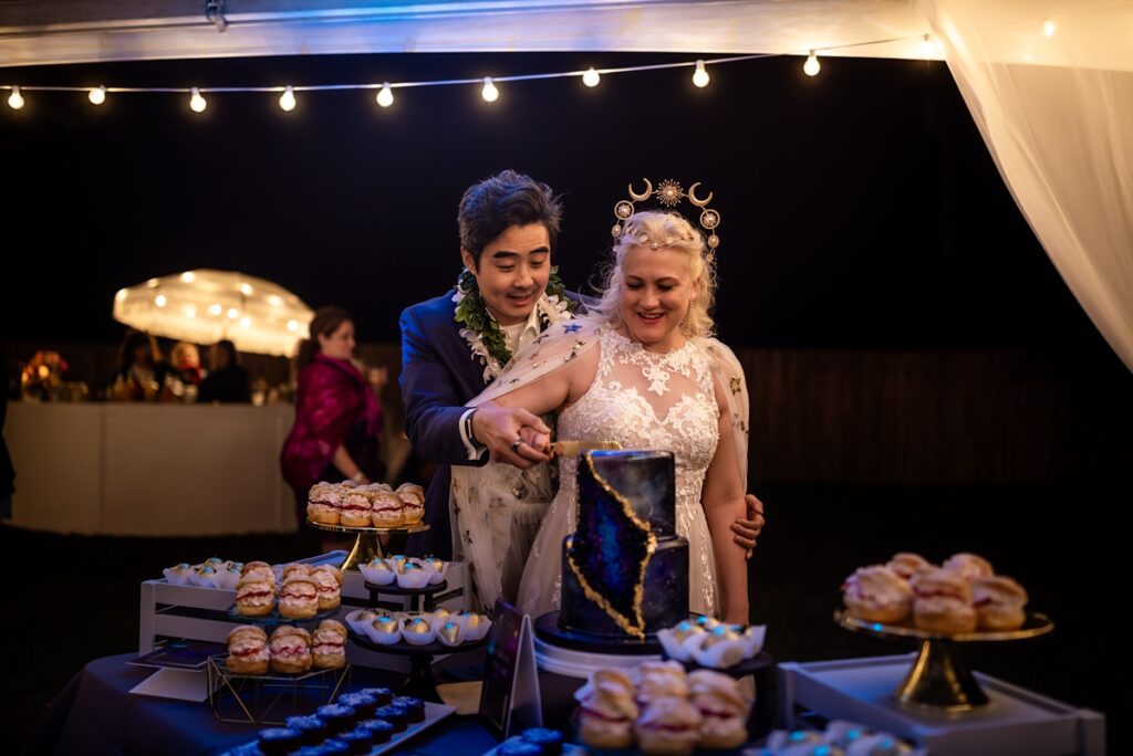 bride and groom cut their cake at Kualoa Ranch Wedding with Iwalani Photography