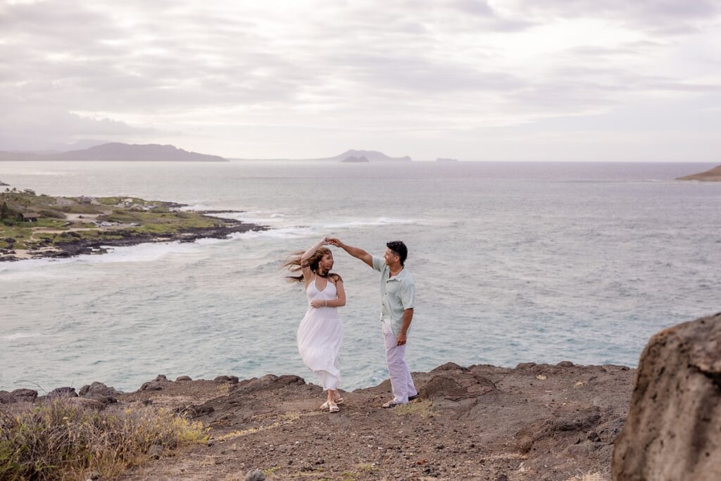 couple on cliff overlooking the ocean taking engagement photos photography by oahu wedding photograper Iwalani Photography